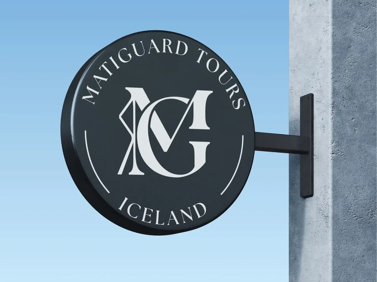 Кругла вивіска бренду Matiguard Tours Iceland з монограмою MG, закріплена на металевому кронштейні біля світлого фасаду будівлі.